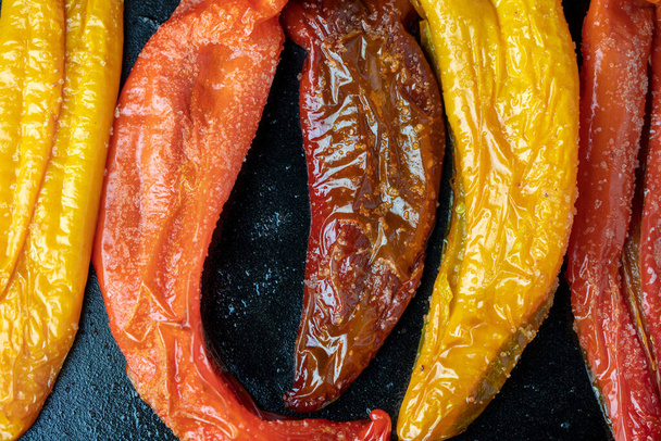 Just roasted orange, red, and purple Poivron peppers cooked in the oven in a cast iron grilling pan - Photo, Image