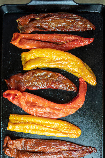 Gerade geröstete orange, rote und lila Poivron-Paprika im Ofen in einer gusseisernen Grillpfanne gekocht - Foto, Bild