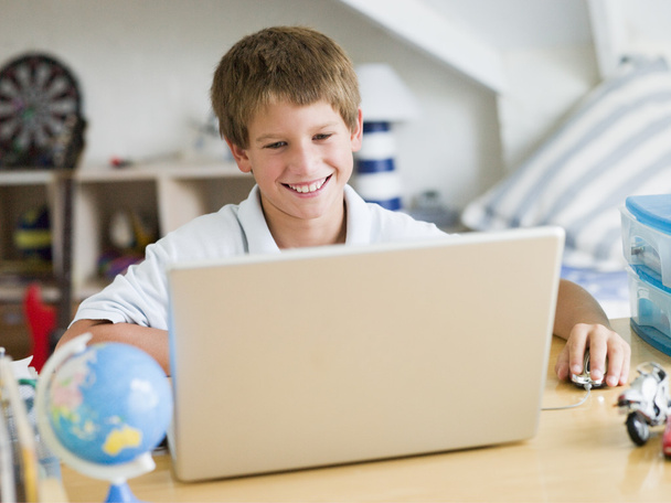 Young Boy Using A Laptop In His Bedroom - Foto, afbeelding