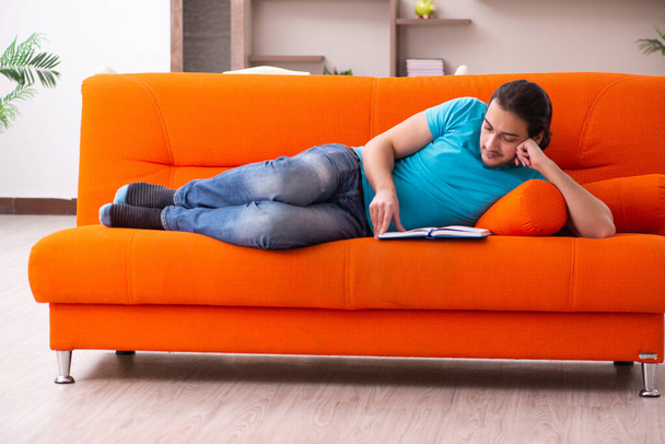 Young male student sitting on the orange sofa - Photo, Image