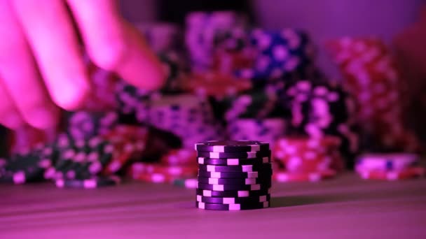 The man plays in the casino. Only chips and hands are visible above the table. The background is very blurry. - Footage, Video