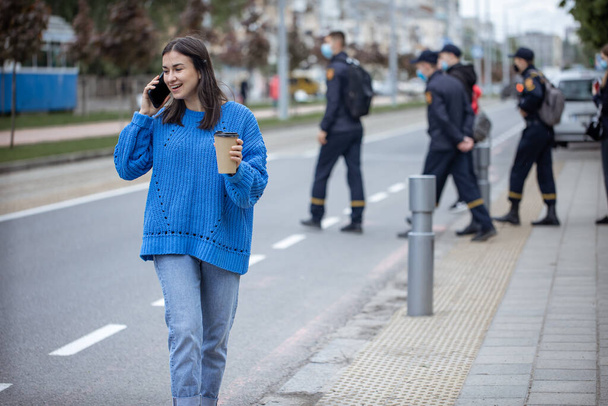 Retrato callejero de una joven hablando por teléfono en la ciudad cerca de la carretera. - Foto, imagen