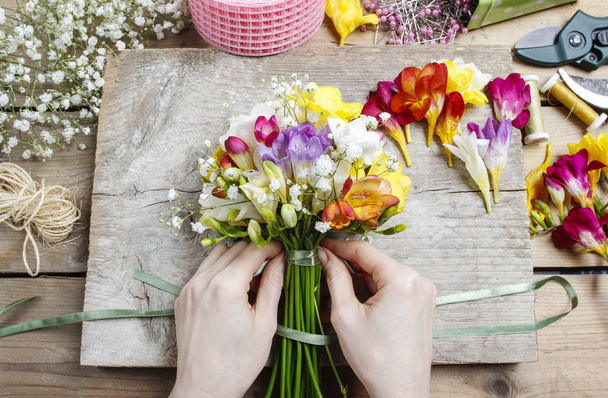 Florist at work. Woman making bouquet of freesia flowers - Photo, image