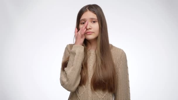 Beyaz stüdyo arka planında gözyaşlarını silen ve başını sallayan genç bir kızın portresi - Video, Çekim