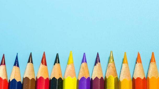 row of colorful pencils on blue background - Foto, afbeelding