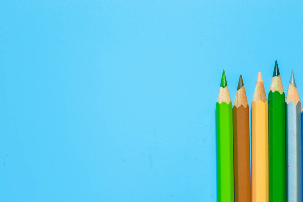 row of colorful pencils on blue background - 写真・画像