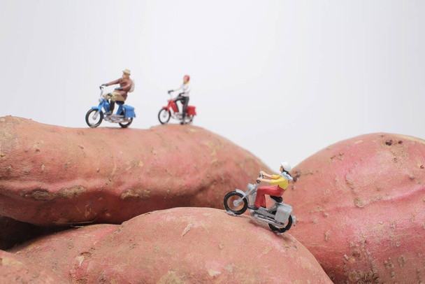 Kleine Figur fährt Motorrad auf den Süßkartoffeln  - Foto, Bild