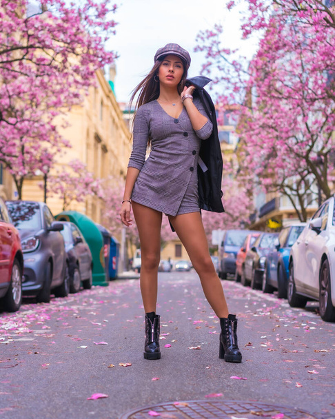 Street Style in the city, brunette Caucasian girl with leather jacket walking in the city with the blossomed trees in spring - Foto, Imagem