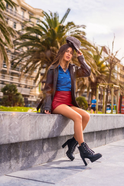 Street Style in the city, a brunette Caucasian girl sitting in a denim shirt, a beret and a red short skirt sitting enjoying the summer holidays - Φωτογραφία, εικόνα