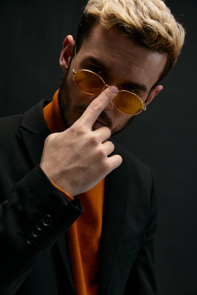 стильні чоловіки випрямляють окуляри на обличчі і помаранчевий светр модель чорного піджака
 - Фото, зображення