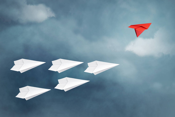 Rotes Papierflugzeug fliegt in eine andere Richtung als das weiße. Bewölkter Himmel. Kopierraum. Das Konzept innovativer Lösungen, Kreativität. Unternehmen. Lebensstil. Hintergrund. - Foto, Bild