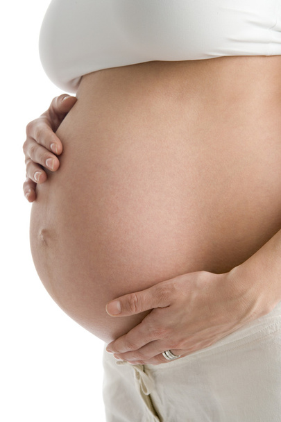Pregnant woman holding exposed belly - Foto, afbeelding