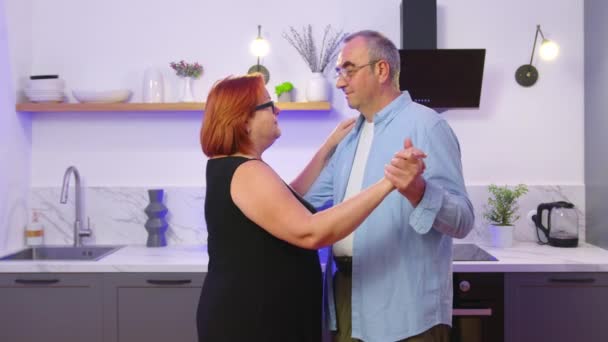 Happy mature senior couple dancing laughing in the kitchen, beautiful romantic middle aged older grandparents relaxing having fun together at home celebrating anniversary enjoy care love tenderness. - Footage, Video