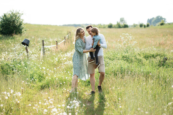 Famille heureuse avec un petit fils enfant qui s'amuse dans une prairie ensoleillée d'été, photo de stock - Photo, image