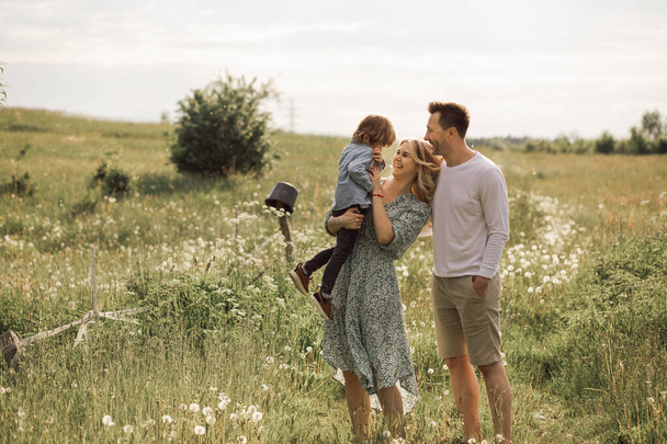 若い家族、お父さん、お母さんと小さな息子のための夏の晴れた日は喜びと幸せになりました。美しい花の牧草地、幸せな家族のコンセプト写真 - 写真・画像