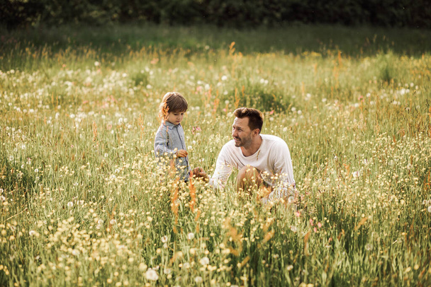 Папа и сын играют в лесу среди цветущих лугов. солнечный день наполнен счастьем - Фото, изображение