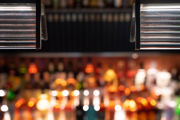 Defocused bar counter with backlit bottles in the background - Valokuva, kuva