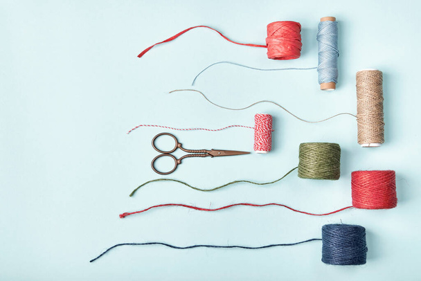 Tijeras y diferentes madejas de cuerdas, cordeles, cuerdas para embalaje y decoración - Foto, Imagen