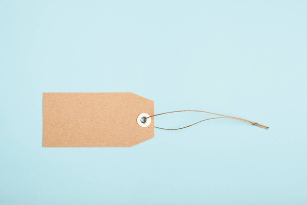 Blank paper price tag with a knotted string on a blue background - Фото, изображение