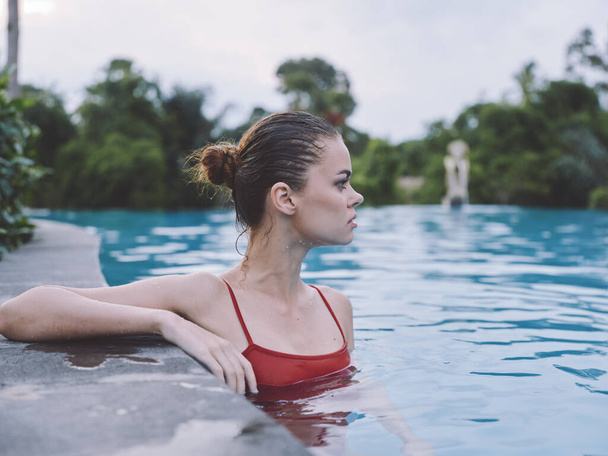 nő úszik a medencében egy piros fürdőruha és frizura modell nyaralás - Fotó, kép