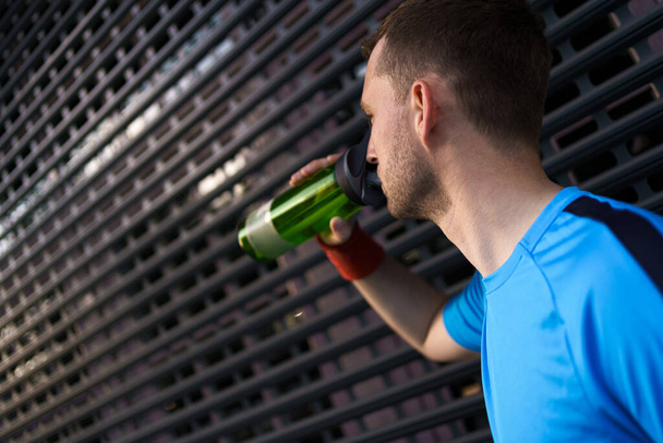Blanke man die water drinkt tijdens oefeningen - Foto, afbeelding