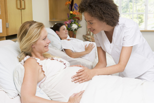 Krankenschwester überprüft Schwangerschaftsbauch und lächelt - Foto, Bild