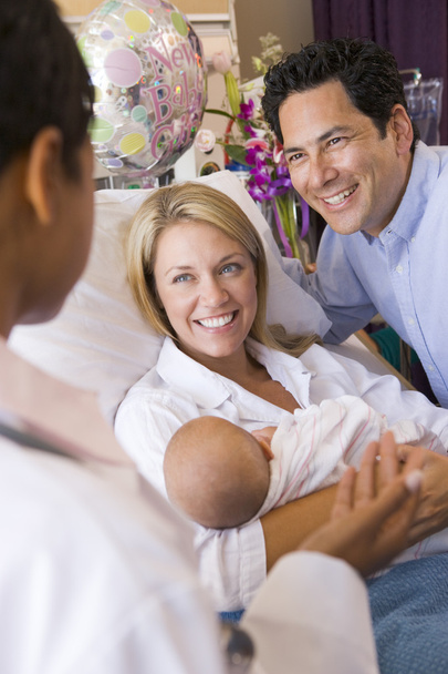 New parents with baby talking to doctor and smiling - 写真・画像