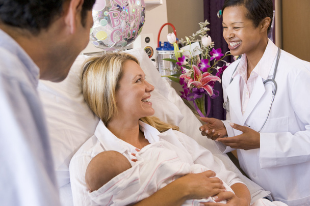 Nuevos padres con bebé hablando con el médico y sonriendo
 - Foto, Imagen