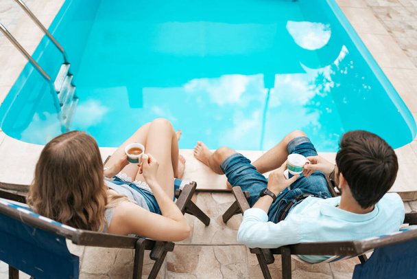 Férfiak és nők együtt töltenek egy kis időt a medence mellett teázgatva. - Fotó, kép