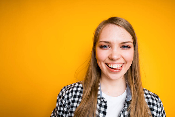 Happy young girl in shirt smiling and laughing showing white teeth and standing on yellow background - Φωτογραφία, εικόνα