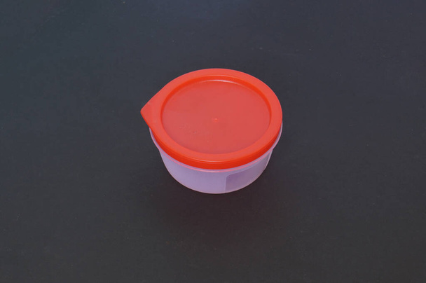Recipiente plástico redondo em um fundo escuro - Foto, Imagem