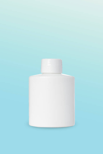 tyhjä valkoinen muovipullo kosmetiikkaan sinisellä pohjalla. Matkijat - Valokuva, kuva