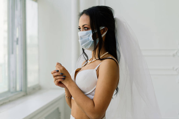 Novia afroamericana en lencería, máscara y por la mañana preparándose para la boda en habitación de hotel - Foto, imagen