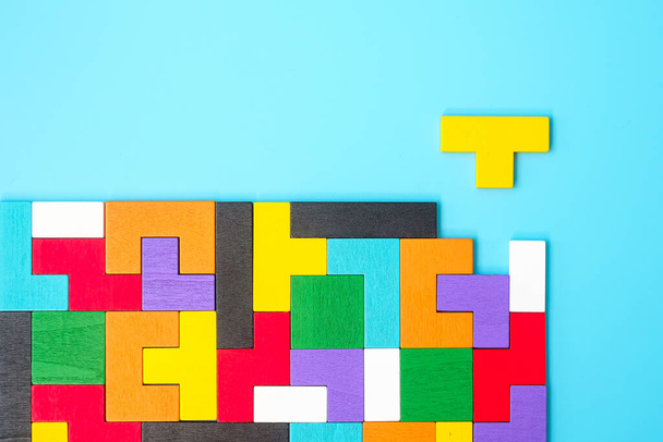 kleurrijke houten puzzelstukjes op blauwe achtergrond, geometrische vorm blok. Begrippen logisch denken, raadsel, oplossingen, rationeel, strategie, wereldlogica en onderwijs - Foto, afbeelding