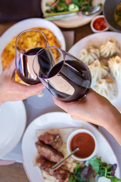 Georgische Restaurant Essen auf dem Tisch Wein in den Händen. Selektiver Fokus. Weiß. - Foto, Bild