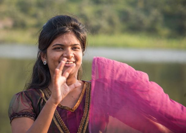 Молода щаслива індійська дівчина грає з рожевим шарфом на вулиці.. - Фото, зображення
