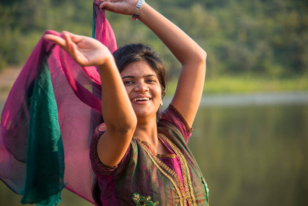 Joven chica india feliz jugando con su bufanda rosa al aire libre. - Foto, Imagen