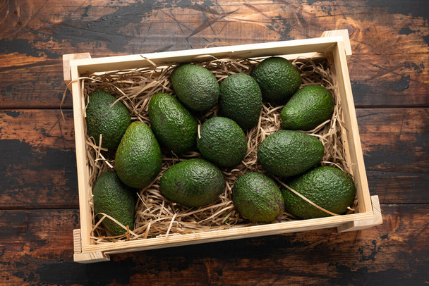 Свіжий авокадо в дерев'яній коробці на сільському столі
 - Фото, зображення