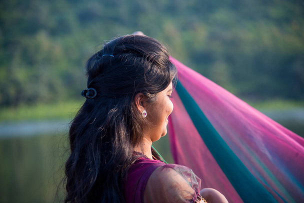 Молодая счастливая индийская девушка играет со своим розовым шарфом на открытом воздухе. - Фото, изображение