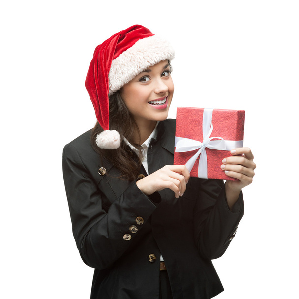 smiling young business woman in santa hat holding red gift - Foto, Bild