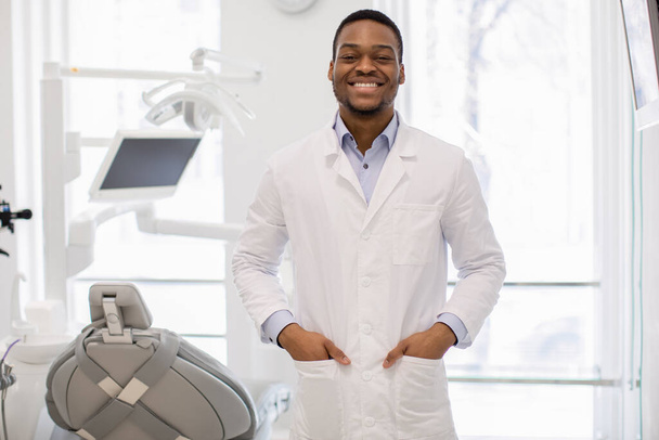Ritratto di bello giovane dentista nero medico in uniforme in posa in clinica - Foto, immagini