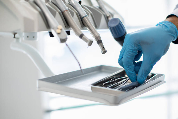 Gros plan de dentistes main dans le gant bleu prenant des outils stomatologiques stériles - Photo, image