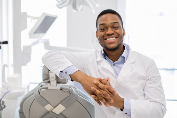 Professionele zwarte orthodont arts poseren op het werk in de moderne kliniek - Foto, afbeelding