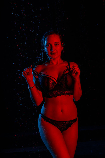 Femme dans la chemise blanche avec goutte d'eau dans une pièce sombre éclairée par la lumière avec de l'eau - Photo, image