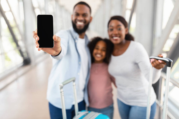Fekete család bemutató üres okostelefon képernyő a repülőtéren - Fotó, kép
