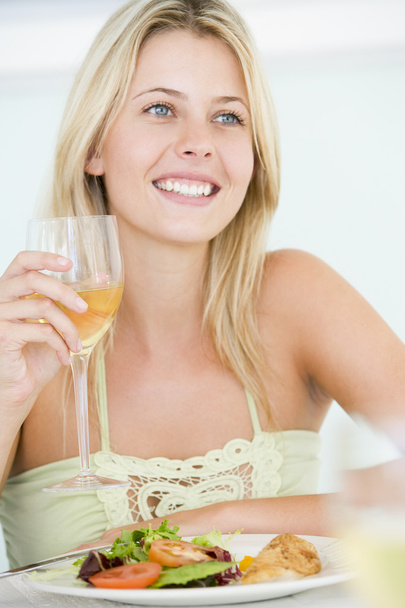 jonge vrouw genieten van maaltijd, maaltijd met een glas wijn - Foto, afbeelding
