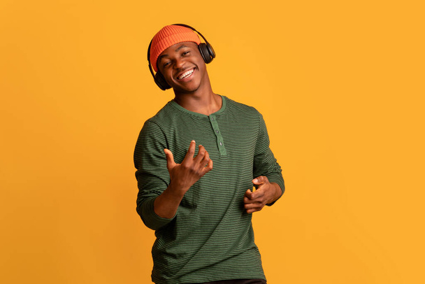 無線電話で音楽を聴く陽気な若いアフリカ系アメリカ人の男 - 写真・画像