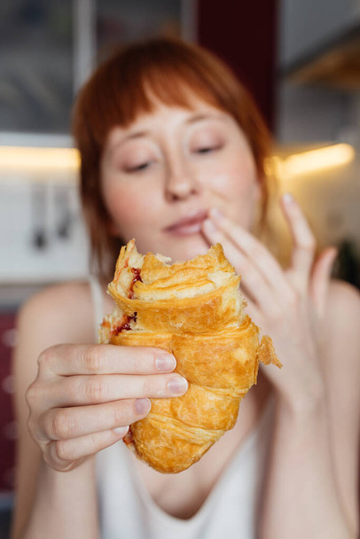 Woman enjoying breakfast while eating croissant with jam at the morning - Foto, Imagen
