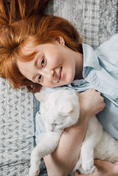 Mulher deitada na cama e abraçando seu gato fofo branco - Foto, Imagem