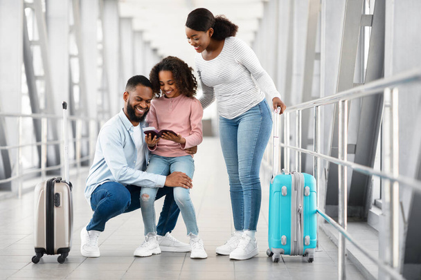 Feliz família negra animada viajando, olhando para documentos no aeroporto - Foto, Imagem